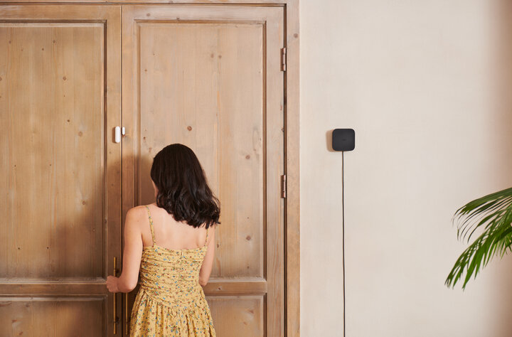 Hub M3 with edge capabilities and Matter support for private, local smart homes on the wall and a woman by the door facing away